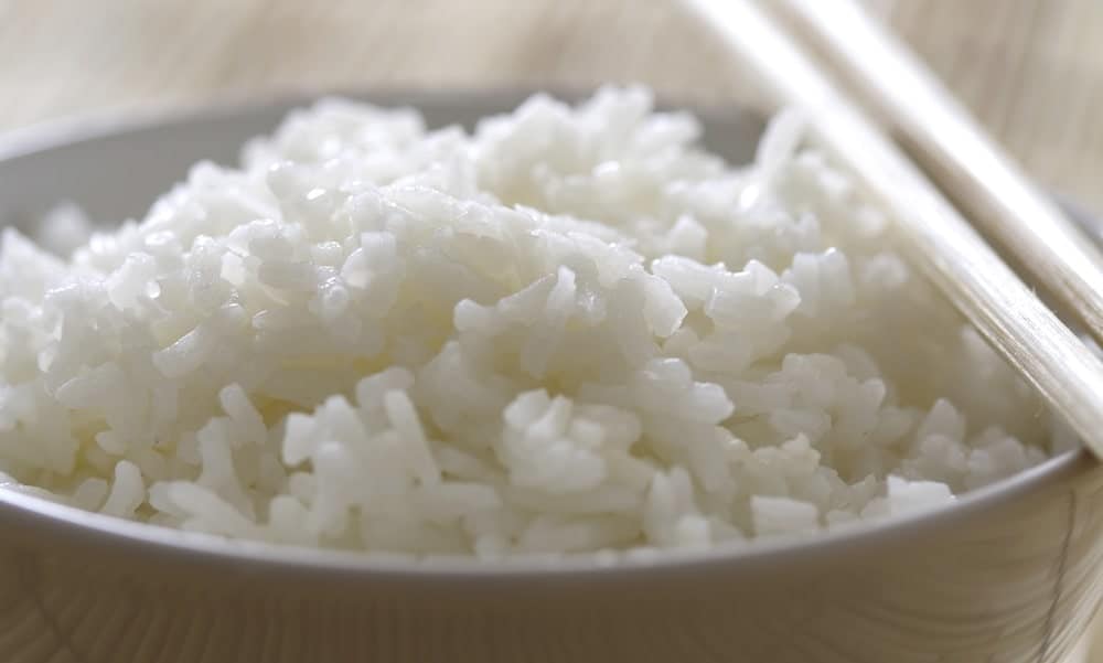 Cooked white rice on a bowl with chopsticks.