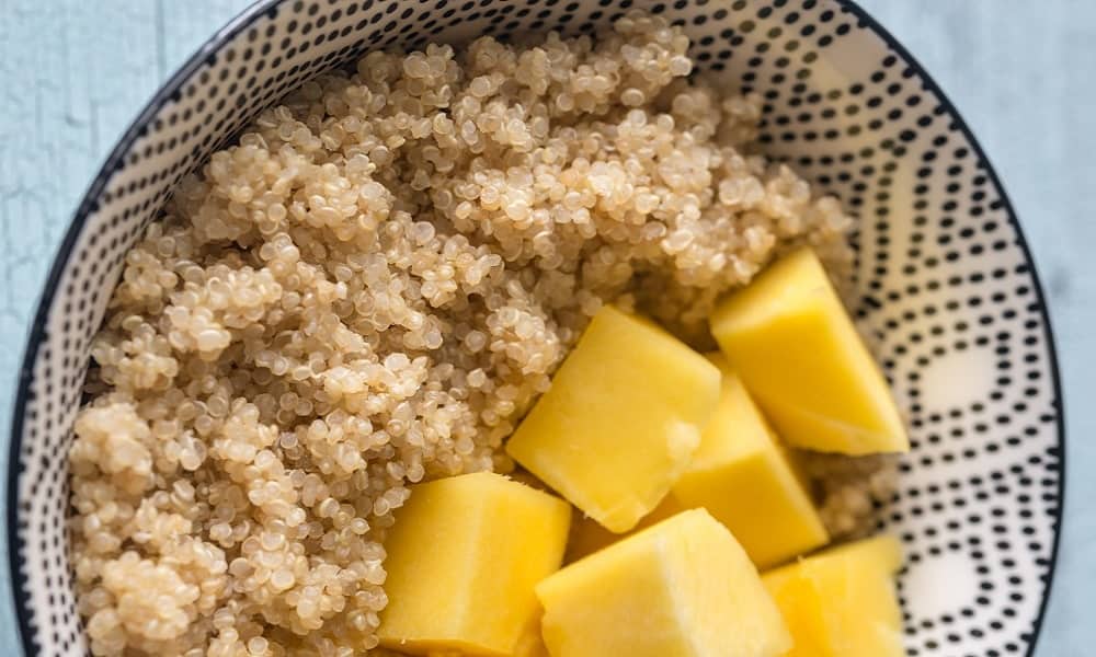 A portion of Quinoa with Mango slices in a bowl.