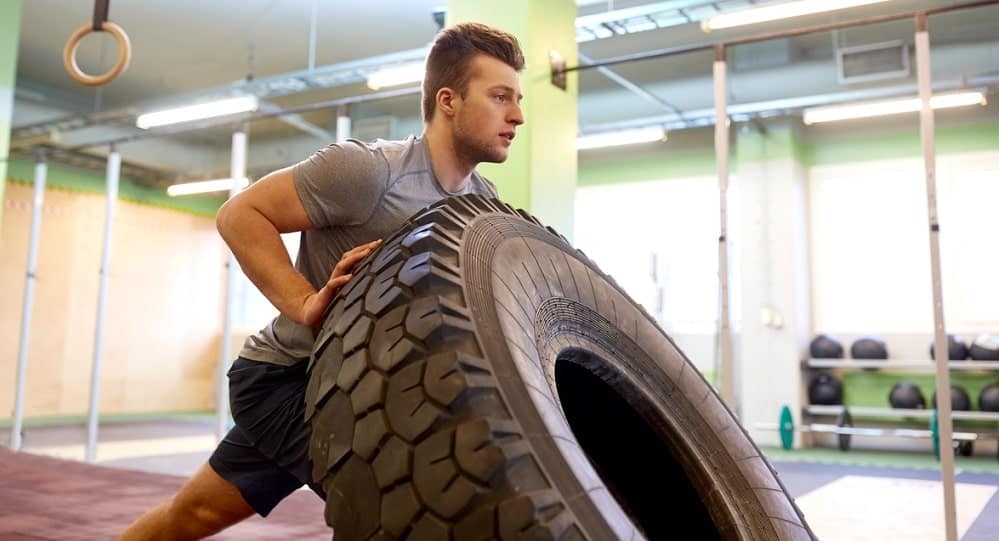 Young man doing a tire flip at the gym.