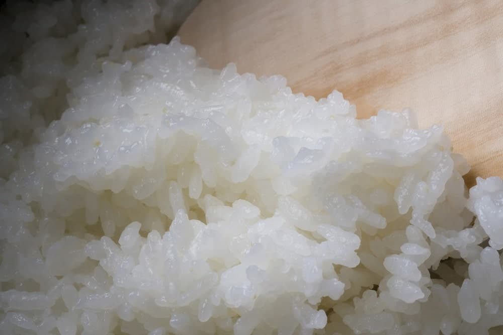 White rice being scooped by a spatula in the rice cooker.