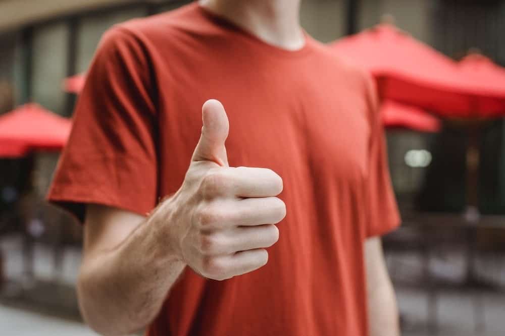 Man wearing a red shirt giving a thumbs up.